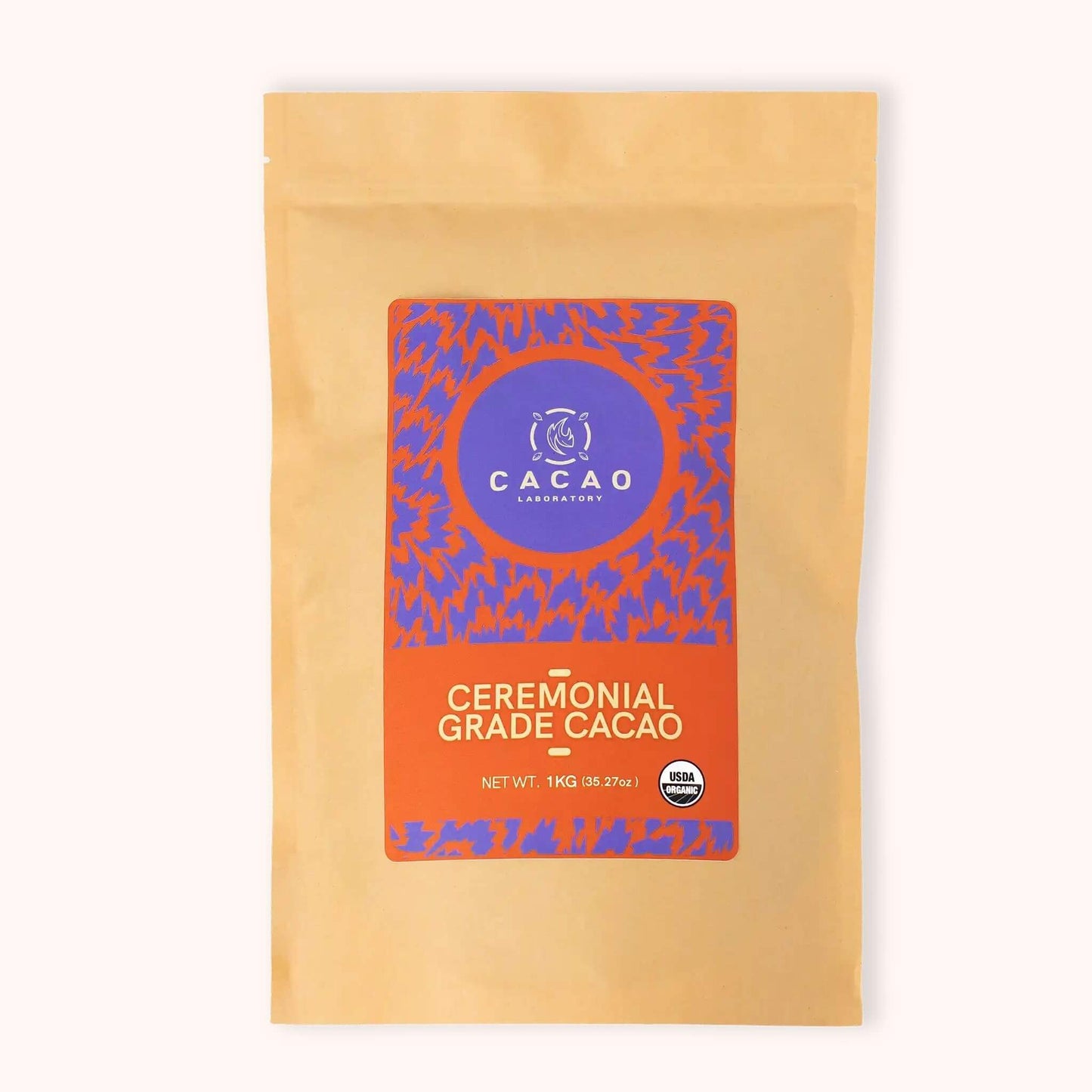 A stand-up pouch of Cacao Company Ceremonial Grade Cacao on a clean white background. The packaging is a warm tan color with a large central label featuring a purple and orange patterned design.