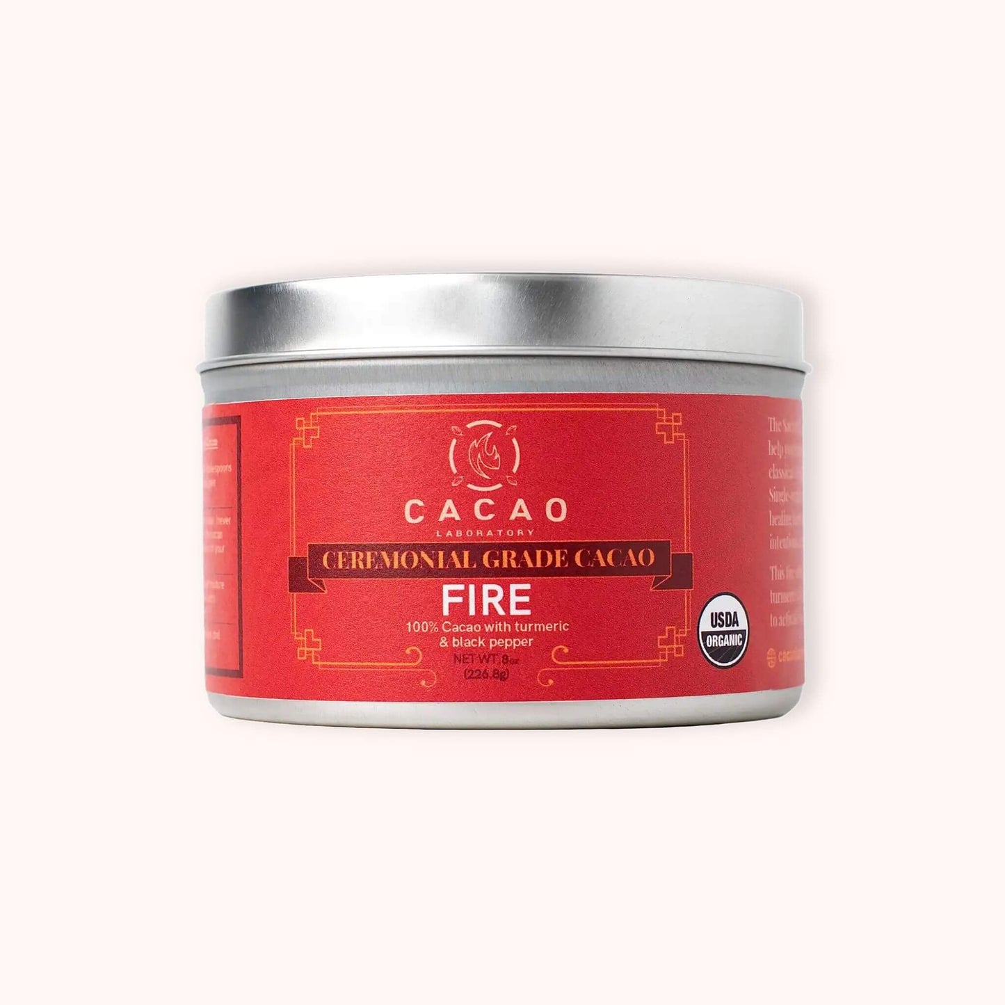 A silver metal tin of Cacao Laboratory Fire Ceremonial Grade Cacao on a light cream background.