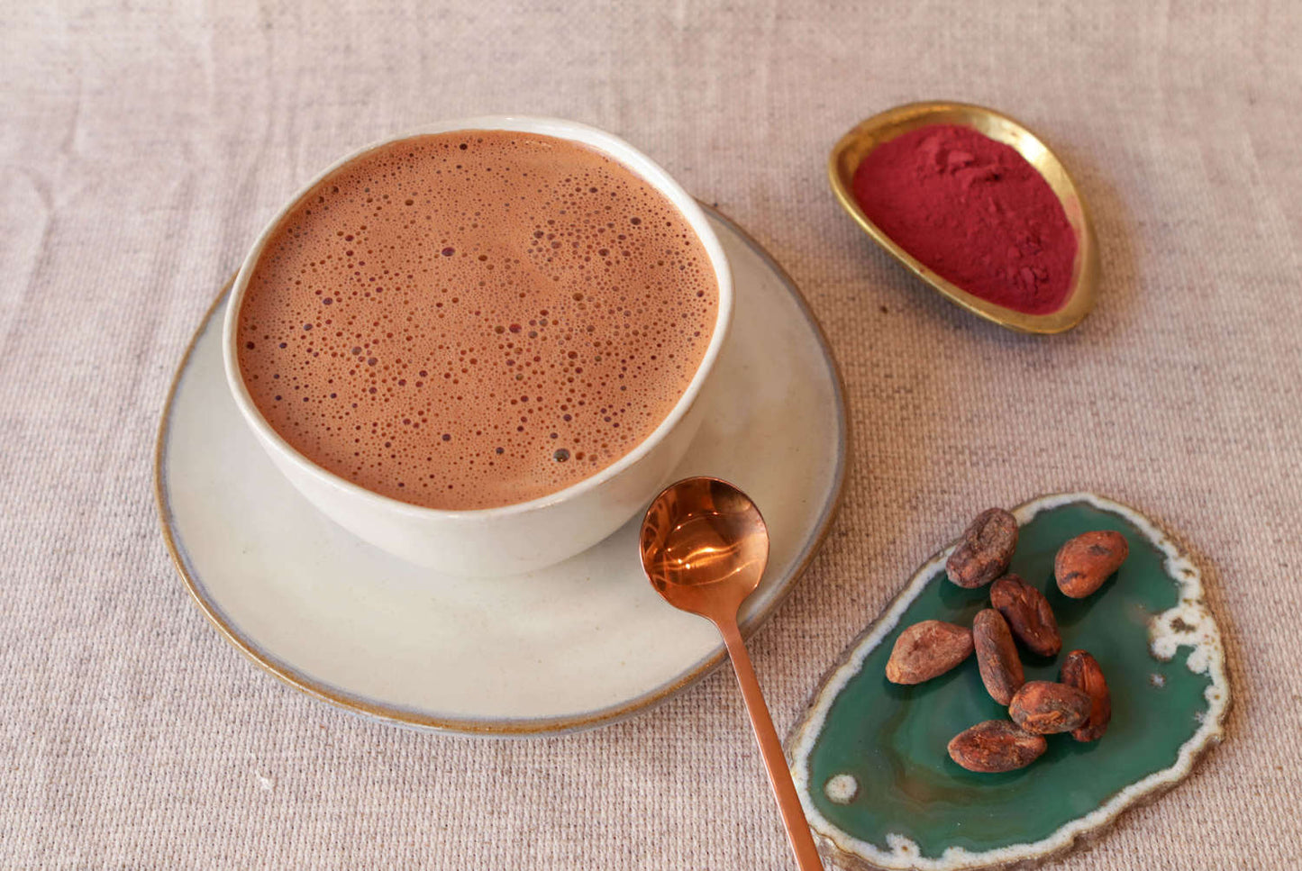 bowl of ceremonial grade cacao with rose powder and some cacao beans on a quartz