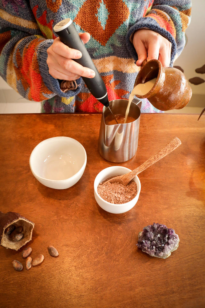 Woman adding oat milk to a ceremonial cacao drink