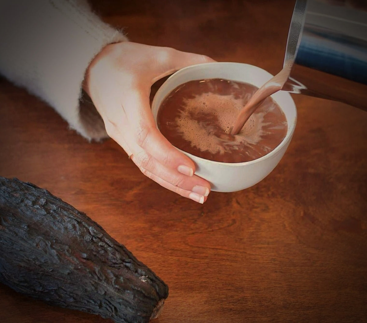 Pouring a cup of ceremonial cacao into a large bowl