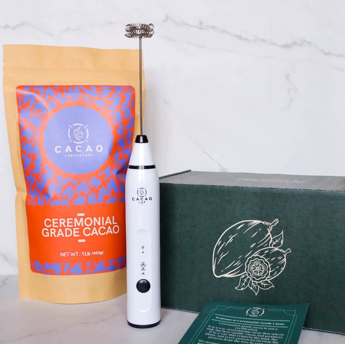 Ceremonial cacao ritual kit with one pound of granulated cacao, a branded frother, cacao guide, and panela sugar