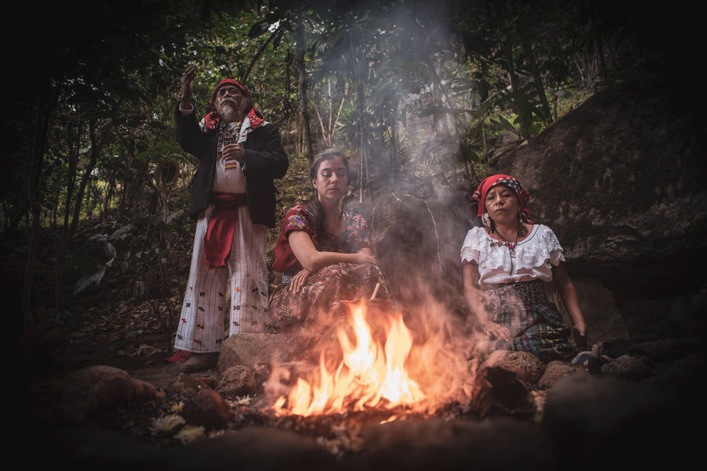 People in indigenous dress around an outdoor fire
