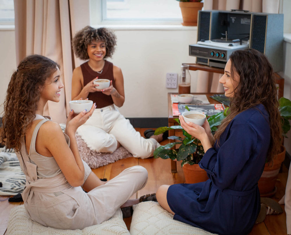 three women enjoying ceremonial cacao while chatting with each other