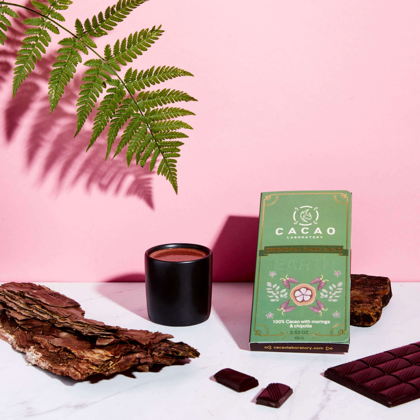 
                  
                    Cacao Laboratory packaging with cacao bars and a cup on a pink background
                  
                