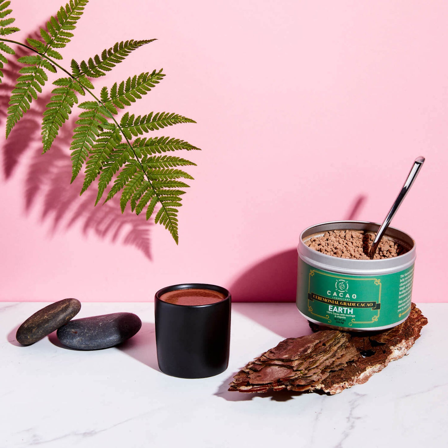 
                  
                    Cacao product with a cup of hot cacao on a pink background
                  
                